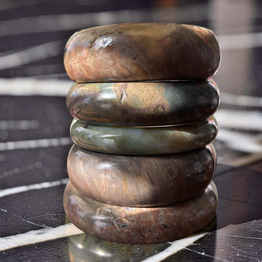 Stack of polished stone rings on a reflective surface with a blurred background