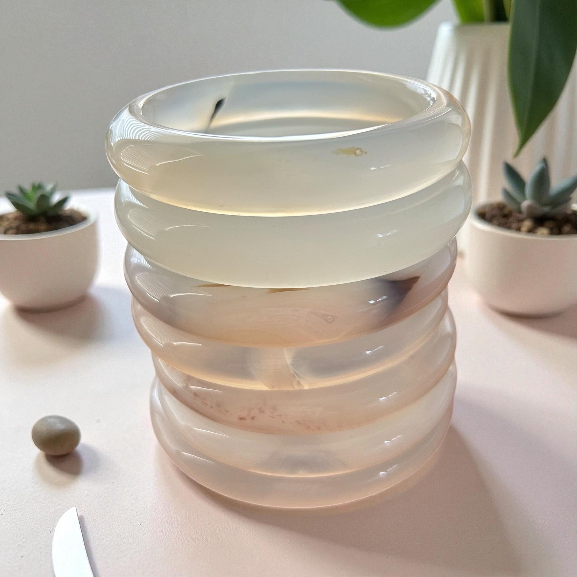 Stacked glass candle holder on a table with plants in the background